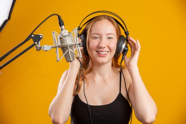 open-air headphones open-back headphones happy woman with headphones on microphone orange background
